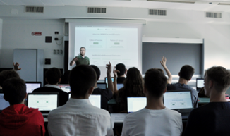 Students in the summer Python STEAM course raise their hands to ask questions to the teacher.